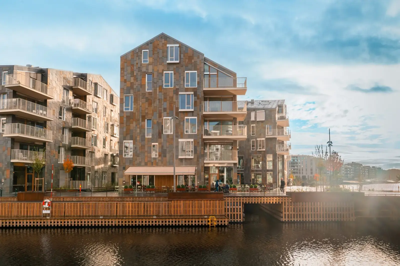 Gavlen på et av husene, med skiferfasaden i høstlys og kanalen foran.