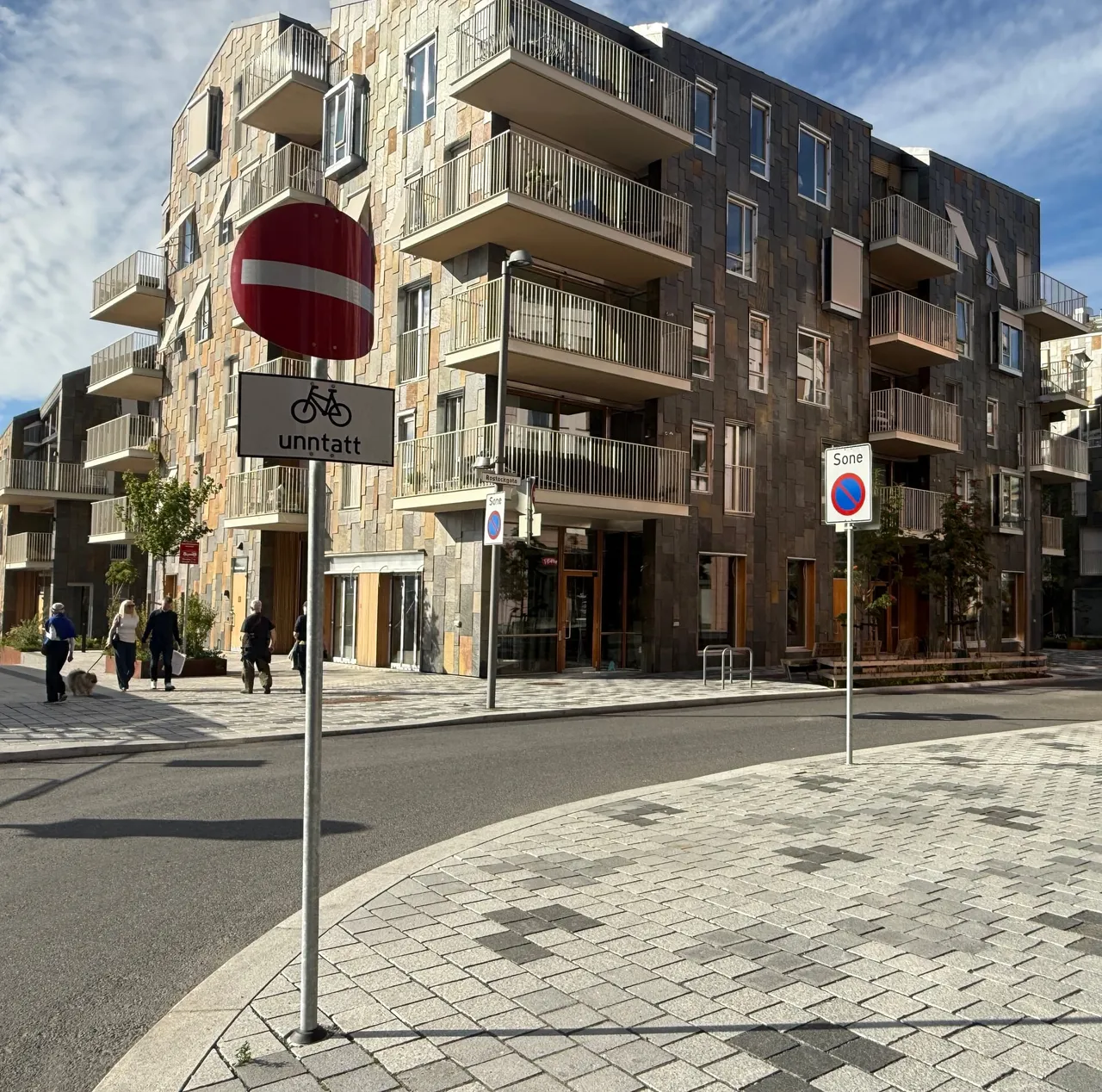 Innkjøring forbudt-skilt med underskiltet «unntatt» og sykkelsymbol ved Rostockgata. Lenger inn i gata står et sone-skilt for parkering forbudt.