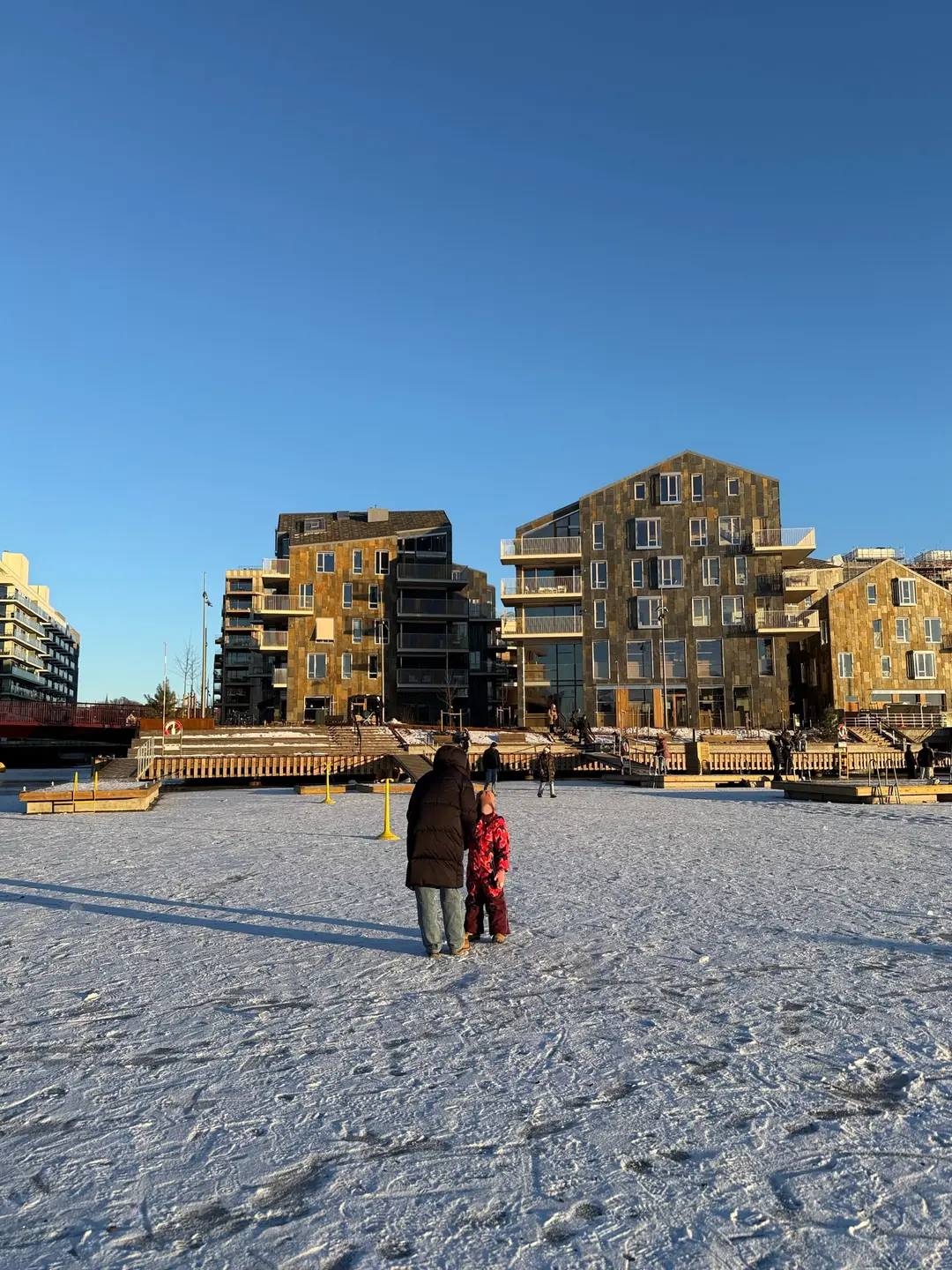 Husene sett fra isen en klar vinterdag, med folk ute på den frosne fjorden.